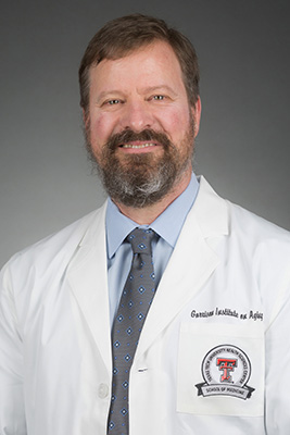 Male TTUHSC researcher smiles in his white coat.
