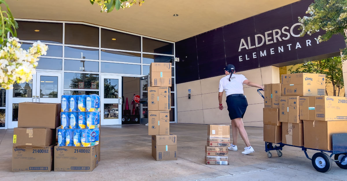 Female TTUHSC medical student pulls a cart of school supplies into an elementary school.
