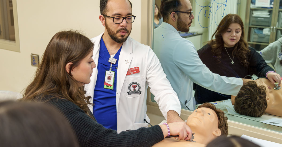 Male TTUHSC medical student shows a female high school student how to use a simulation manikin.