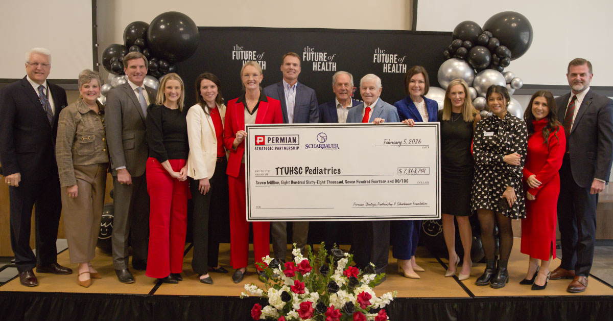 Large group of people stand on stage and hold a large presentation check.