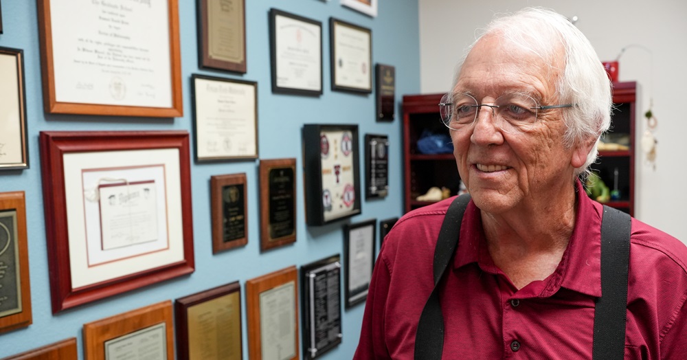 Samuel Prien, Ph.D., looking at a wall of accomplishments