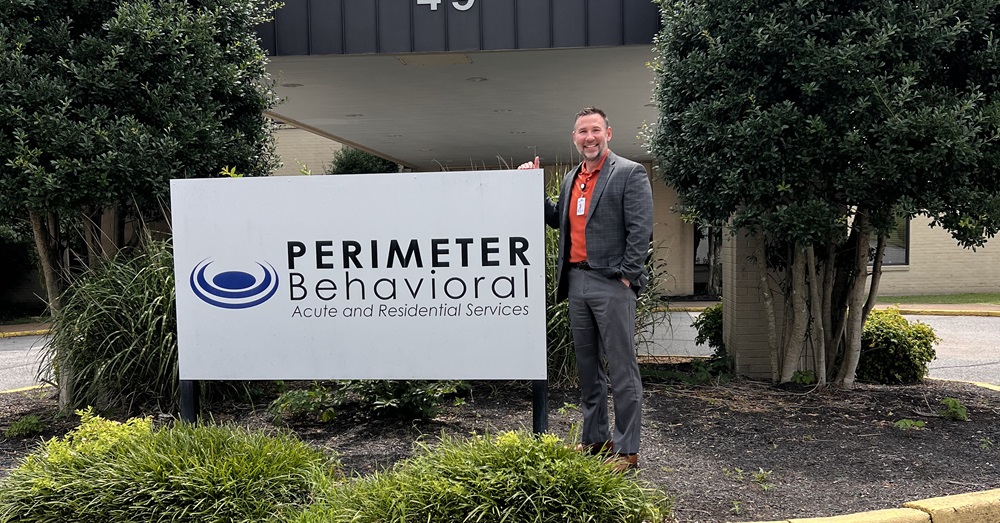 man standing in front of a sign outside that reads "Perimeter Behavioral"