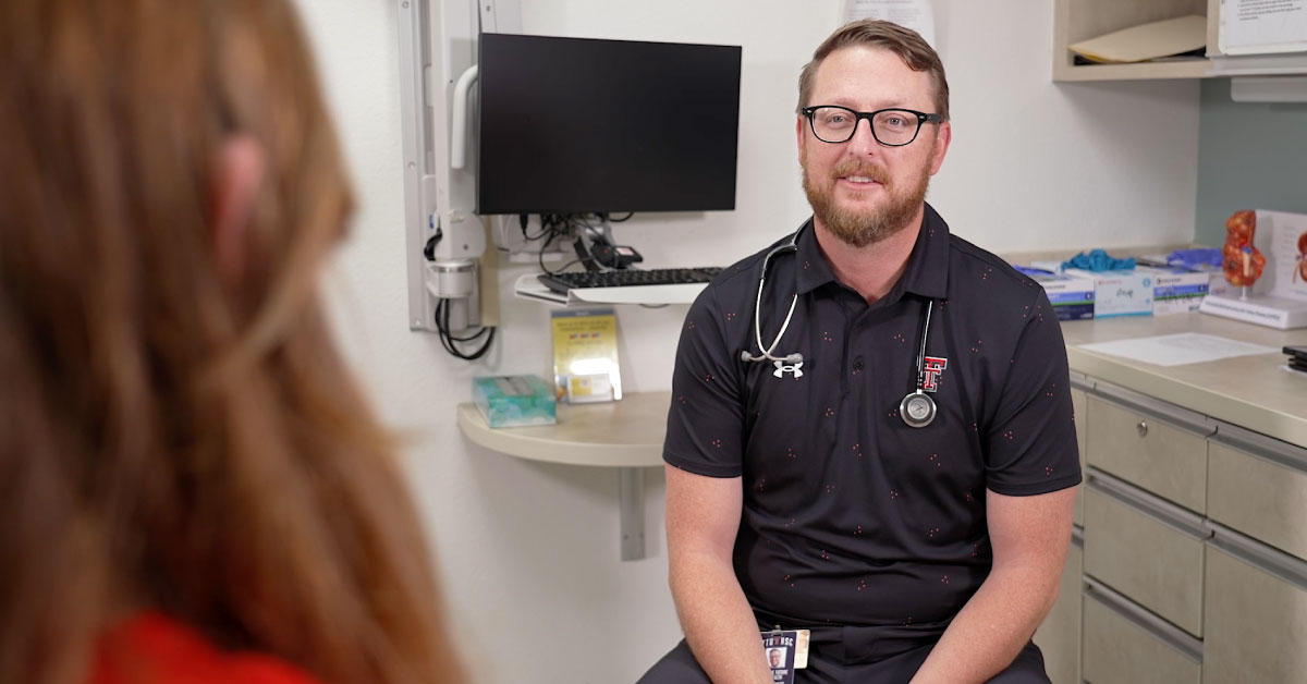 Male physician talks to a patient in the exam room.