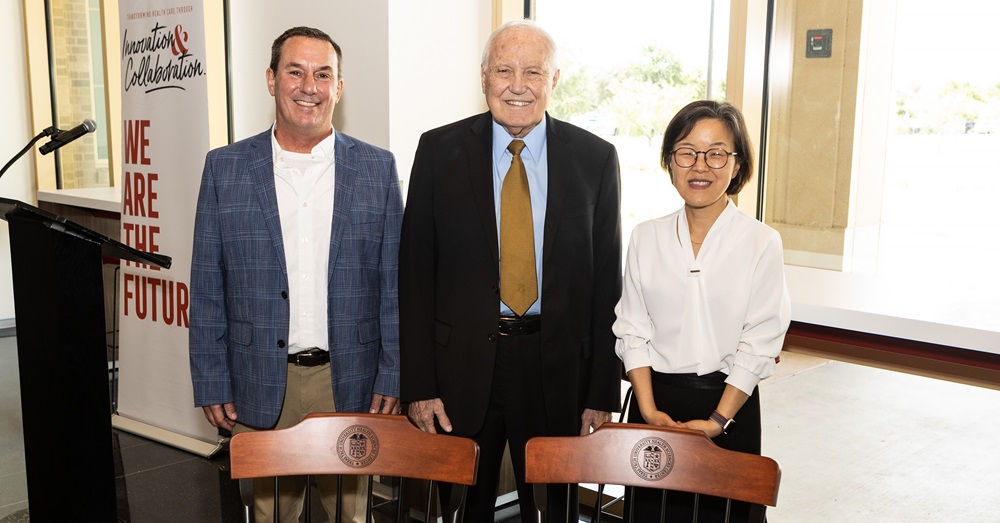 three people standing behind engraved chairs