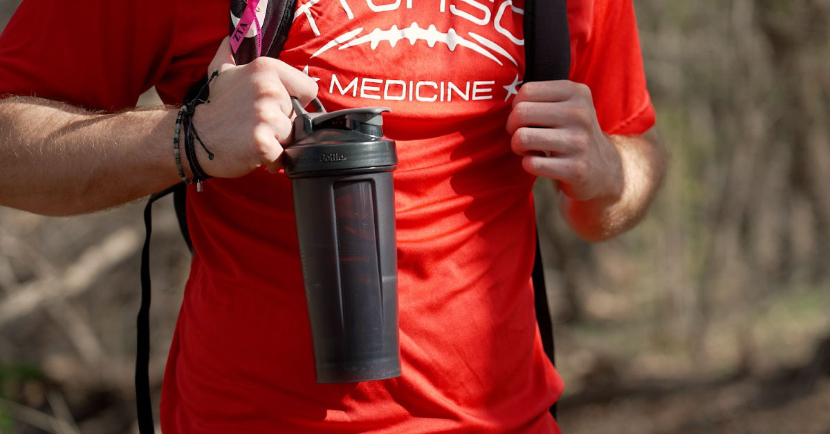 Male student wears a red t-shirt and holds a black refillable bottle.