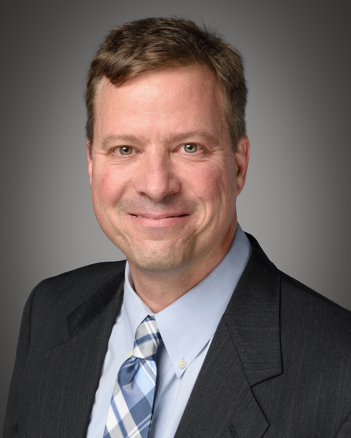 Lance R. McMahon wears a suit and tie.