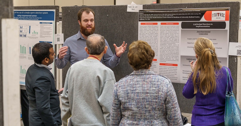 student scientist presents poster to group of onlookers