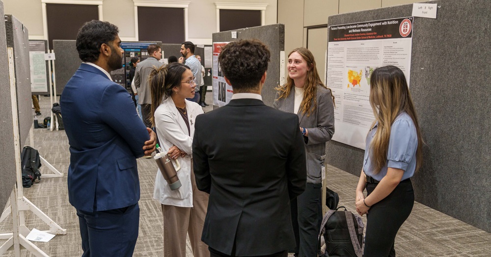 student scientist presents poster to group standing in circle