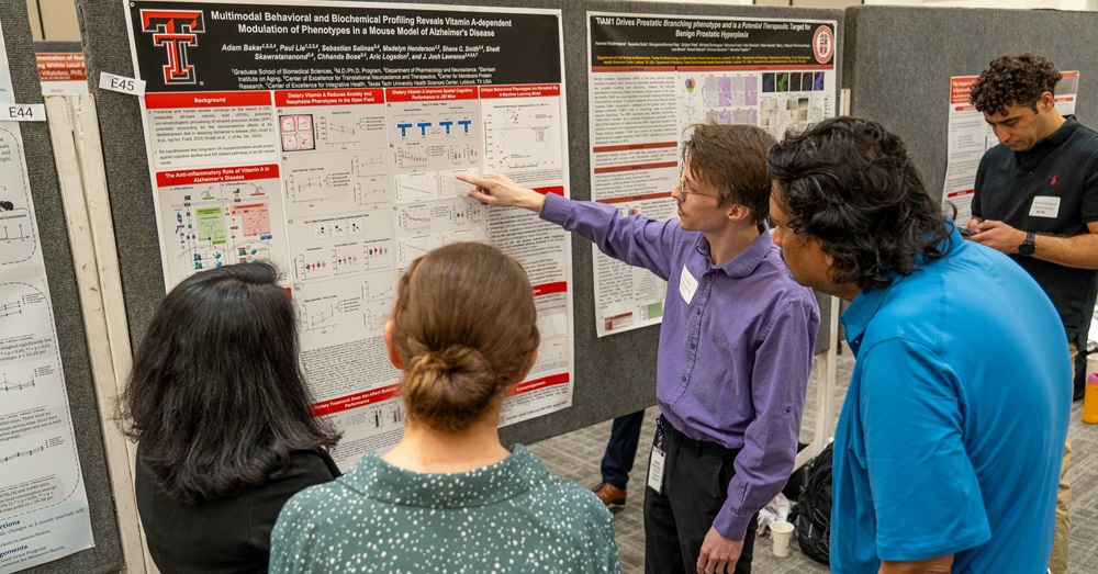 student puts on a poster presentation for two listeners