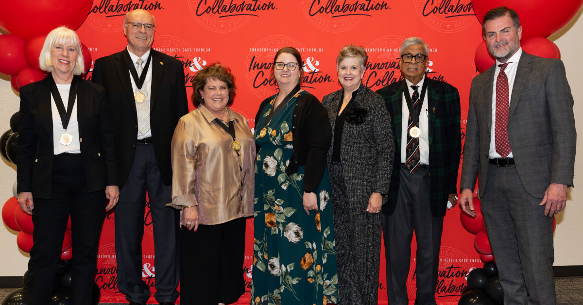 Several people stand in front of a TTUHSC photo backdrop.