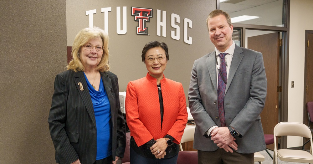 three people standing in front of a ttuhsc sign 