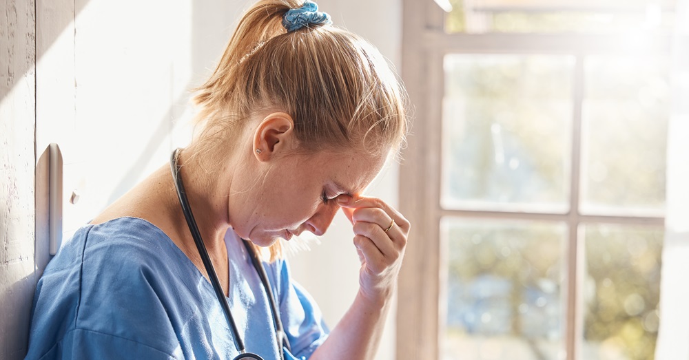 woman in scrubs looking stressed