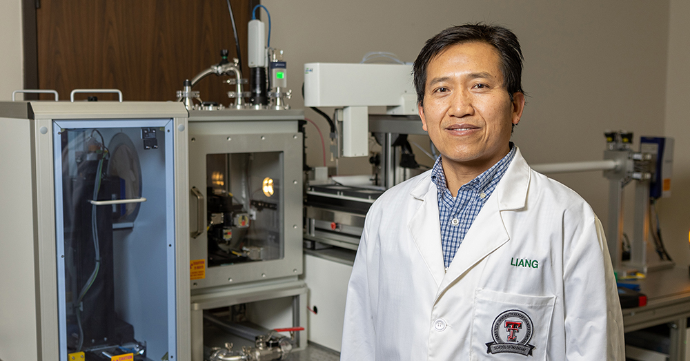 Hongjun “Henry” Liang, Ph.D., standing in front of scientific equipment