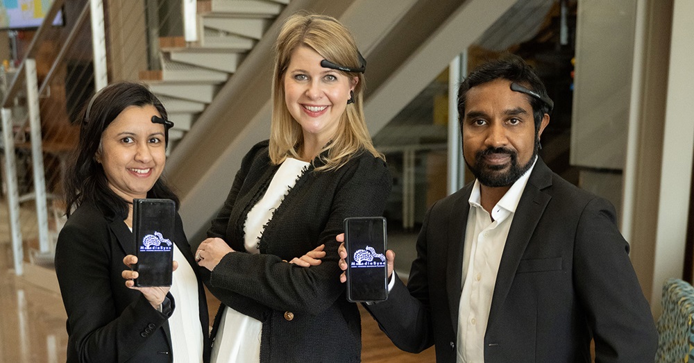 three people stand holding pieces of technology