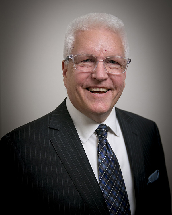 Brian Schroeder wears a suit and tie and smiles.