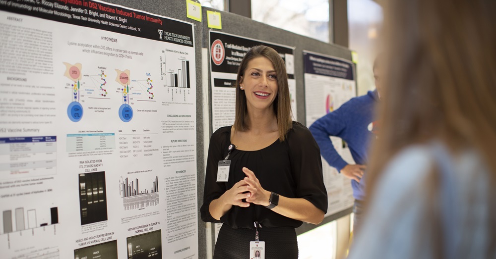 woman giving a presentation in front of a scholarly poster