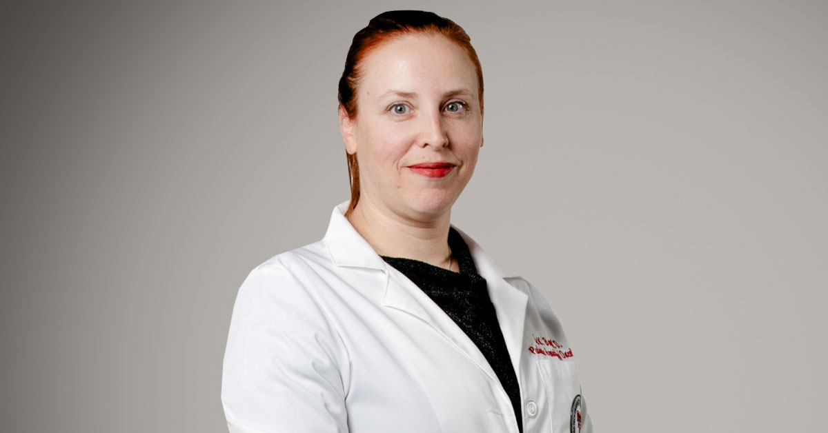 Woman wears white coat.