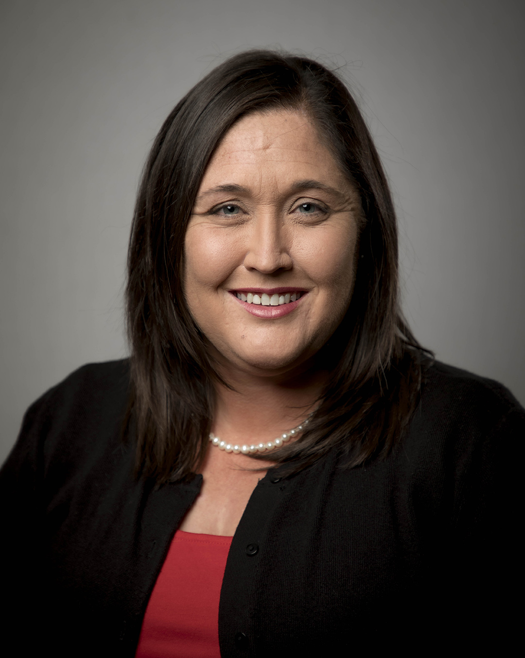 Woman wears red shirt and black coat.