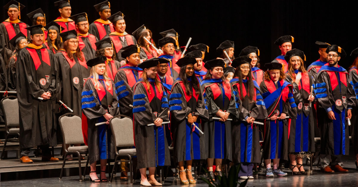 Group of TTUHSC biomedical sciences graduates stand on stage.