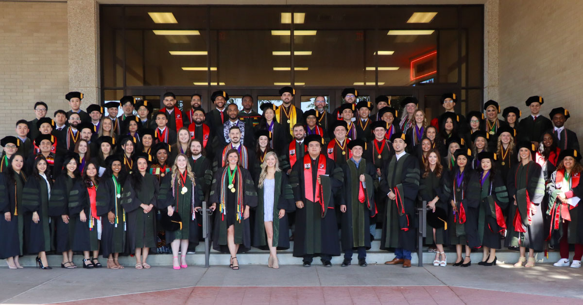 Large group of TTUHSC pharmacy students wear their graduation caps and gowns and pose for a group photo.