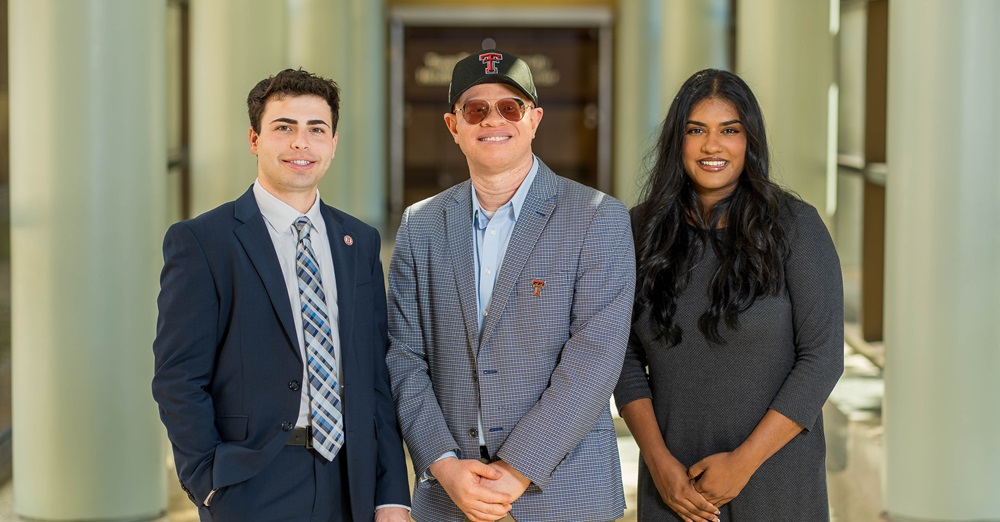 three people stand for a group photo
