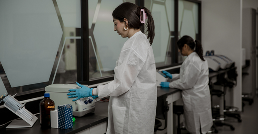 woman working in a lab in a white coat and gloves