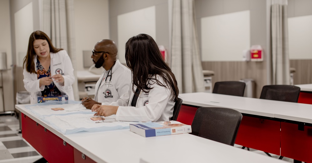 three health care professionals sit at the end of a long table