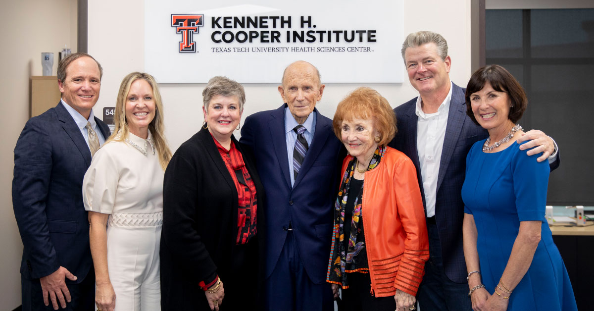 Several people stand in front of a sign that reads, "Kenneth H. Cooper Insitute."