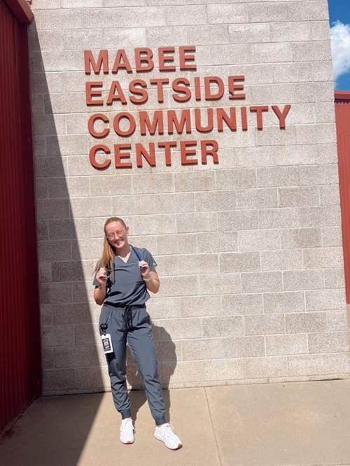 woman in scrubs in front of a community center