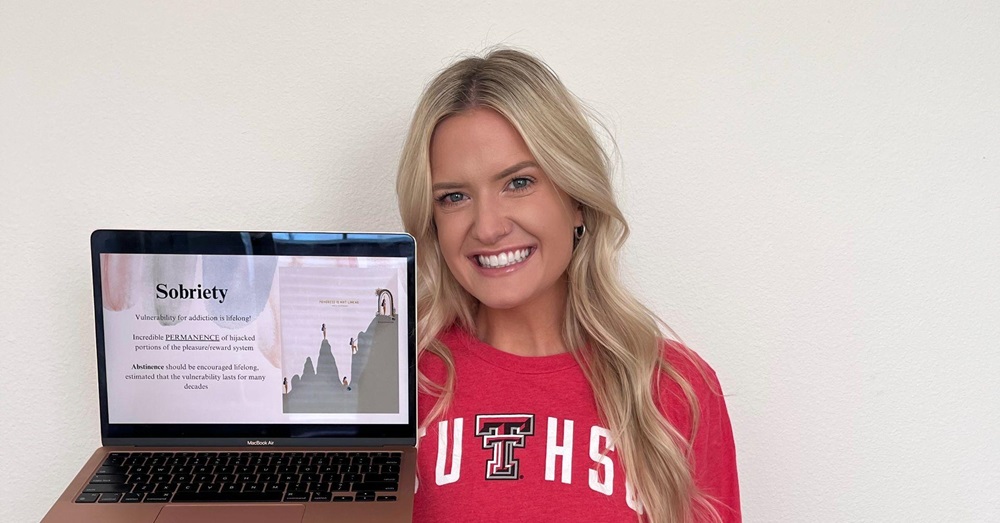 woman holding laptop with the word "sobriety" displayed