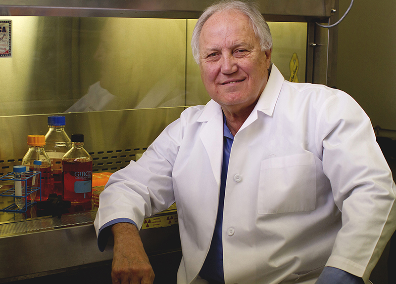 Male TTUHSC researcher wears a white coat and sits in his lab.