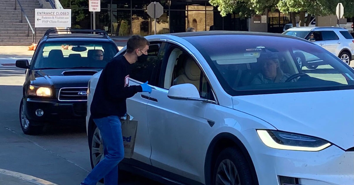 Volunteer receives medication from cars at a drive-thru event.