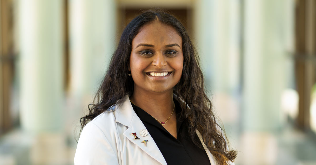 Woman stands in hallway and smiles.